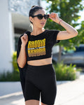 Woman wearing a black crop top with 'Baddle Beyond' text and black shorts outdoors.