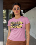 Woman wearing a pink t-shirt with 'Baddie with a Legacy' text.